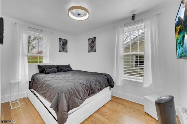 bedroom featuring wood finished floors, multiple windows, and baseboards