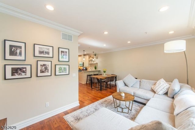 living room featuring crown molding, recessed lighting, wood finished floors, and visible vents