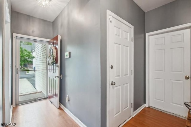 entrance foyer featuring wood finished floors, a chandelier, and baseboards