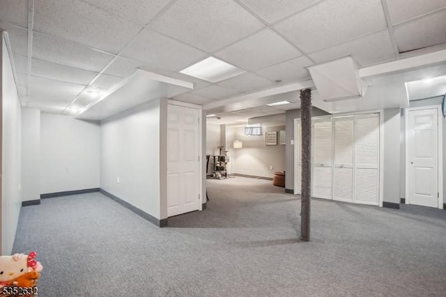 finished basement featuring carpet flooring, baseboards, and a drop ceiling