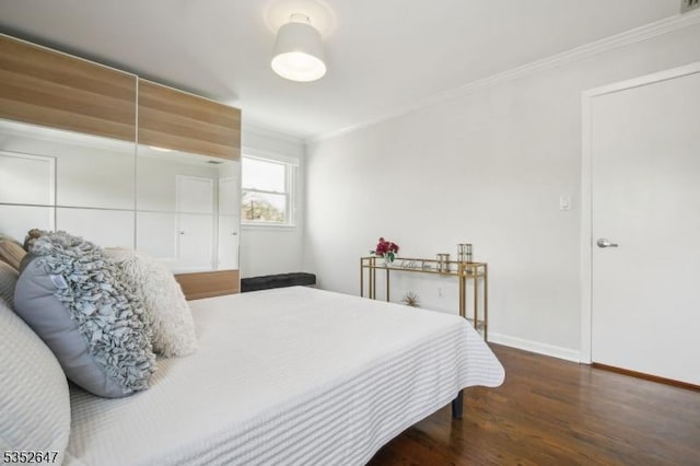 bedroom with baseboards, ornamental molding, and wood finished floors