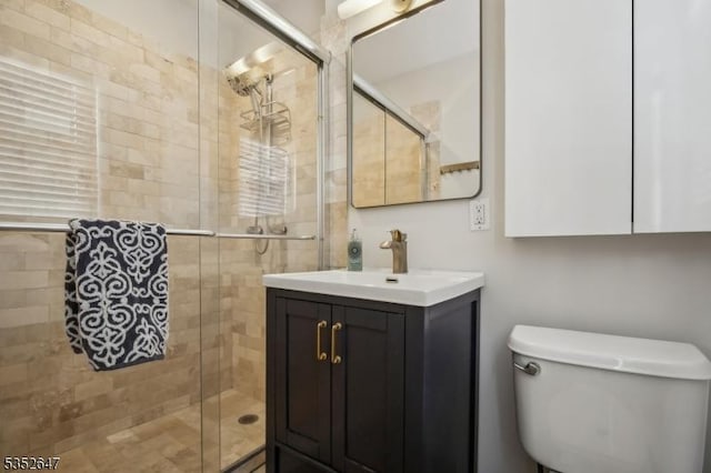 full bathroom featuring vanity, a stall shower, and toilet