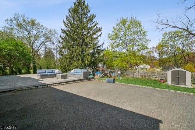 view of patio featuring fence, an outdoor structure, an outdoor hangout area, a playground, and a storage unit