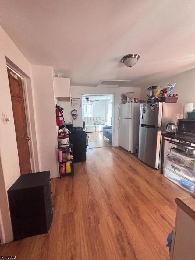 interior space featuring freestanding refrigerator, black microwave, ceiling fan, and wood finished floors