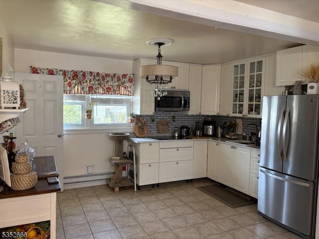 kitchen featuring white cabinets, a sink, a baseboard heating unit, light tile patterned flooring, and appliances with stainless steel finishes