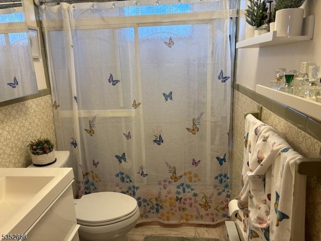 bathroom featuring tile walls, vanity, a shower stall, and toilet