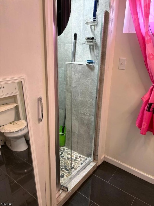 bathroom with tile patterned flooring, a stall shower, and toilet