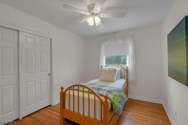 bedroom with wood finished floors, a closet, a ceiling fan, and baseboards