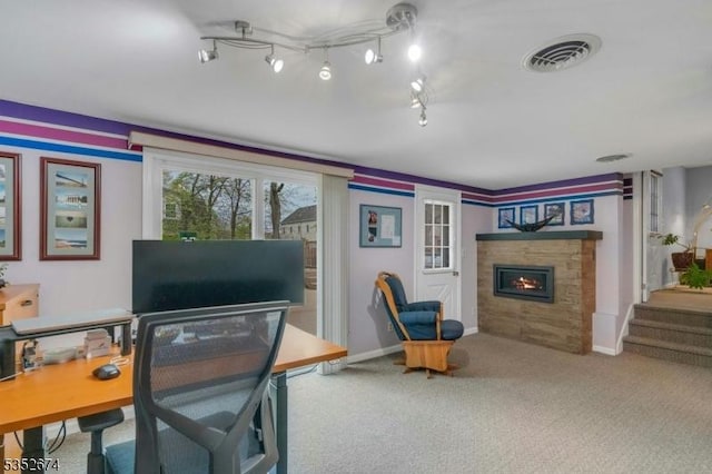 carpeted office featuring a warm lit fireplace, visible vents, and baseboards