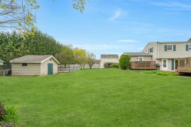 view of yard with an outdoor structure, a fenced backyard, and a deck