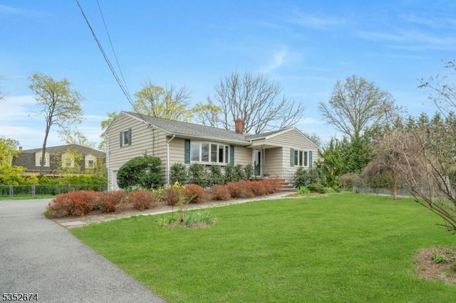 single story home featuring fence, a front lawn, a chimney, and a garage