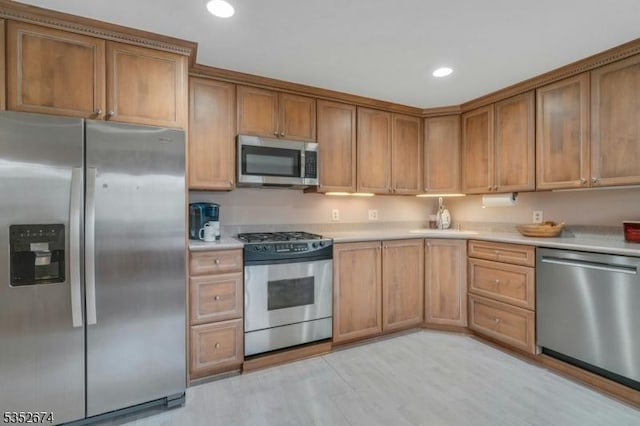 kitchen featuring recessed lighting, light wood-style floors, brown cabinetry, light countertops, and appliances with stainless steel finishes