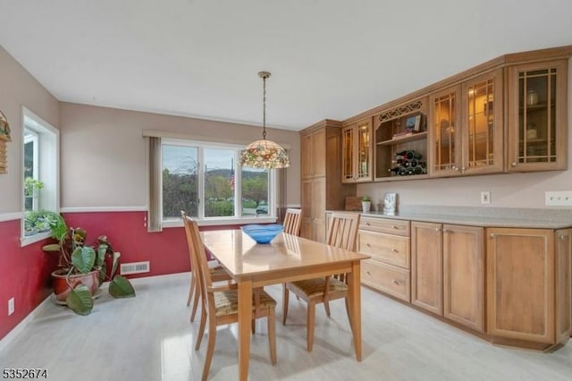 dining space with baseboards, light wood finished floors, and visible vents