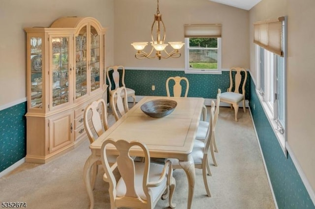 dining area featuring light colored carpet, an inviting chandelier, vaulted ceiling, and wallpapered walls