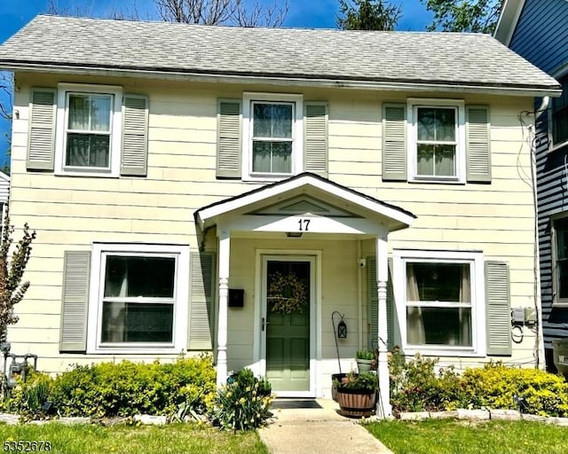 colonial home featuring roof with shingles