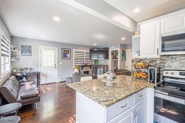 kitchen featuring open floor plan, white cabinetry, light stone counters, appliances with stainless steel finishes, and backsplash