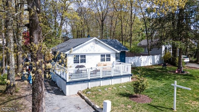 back of property featuring fence, a yard, and a deck