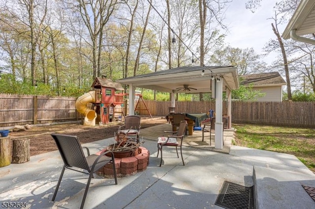view of patio featuring a fenced backyard, a ceiling fan, a playground, a gazebo, and an outdoor fire pit