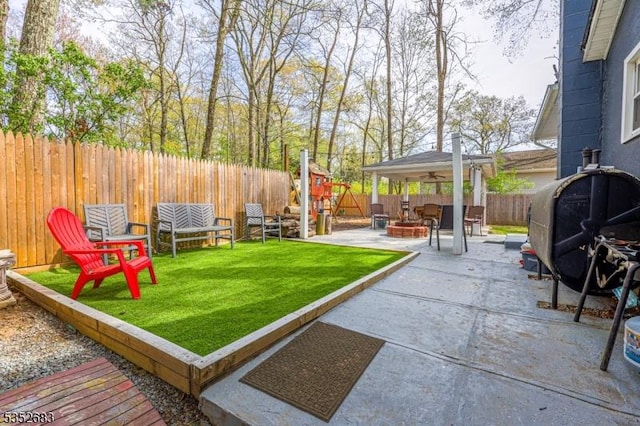 view of yard with a fenced backyard, a ceiling fan, a fire pit, and a patio area