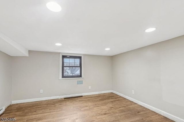 basement with baseboards, recessed lighting, a baseboard radiator, and wood finished floors