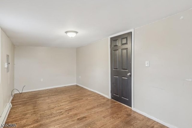 empty room featuring baseboards, wood finished floors, and baseboard heating