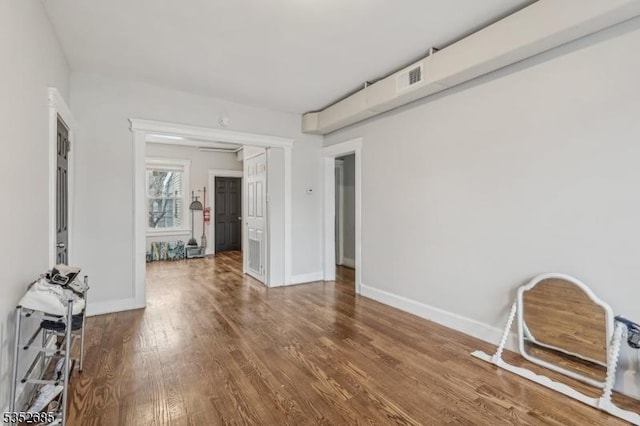 unfurnished room featuring baseboards, wood finished floors, and visible vents