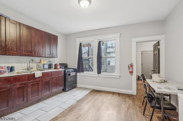 kitchen with a sink, light wood-style flooring, gas stove, and light countertops