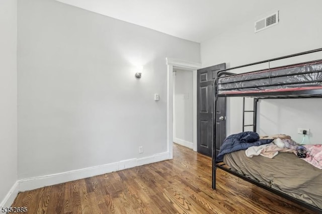 bedroom featuring visible vents, baseboards, and wood finished floors