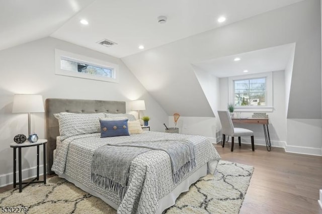 bedroom with lofted ceiling, wood finished floors, multiple windows, and visible vents