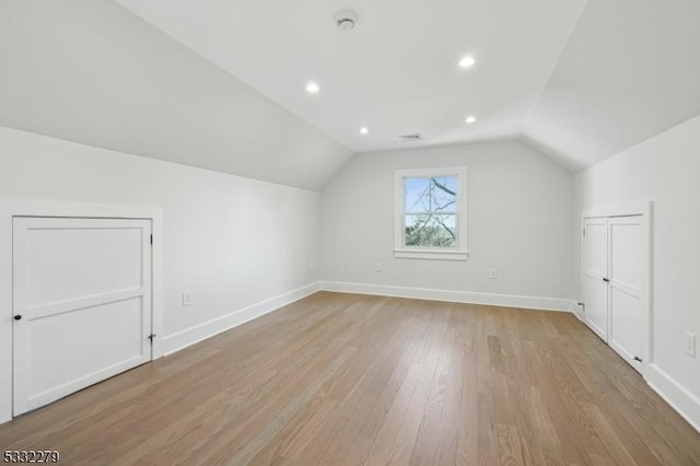 additional living space with light wood finished floors, vaulted ceiling, baseboards, and recessed lighting