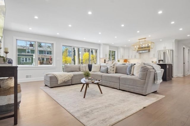 living room with visible vents, baseboards, wood finished floors, and recessed lighting