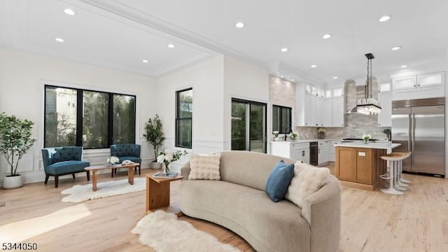 living room featuring recessed lighting, light wood-style floors, and ornamental molding