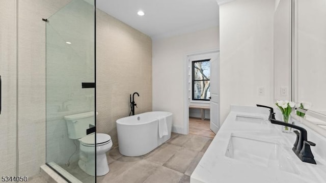 bathroom with double vanity, a soaking tub, toilet, and a sink