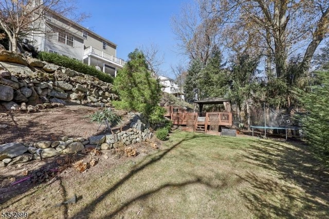 view of yard featuring a gazebo, a deck, and a trampoline