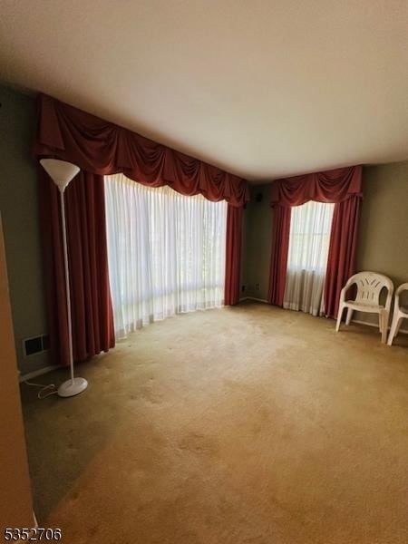 unfurnished room featuring visible vents and light carpet