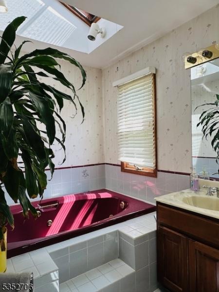 bathroom featuring wallpapered walls, tile patterned floors, vanity, and a relaxing tiled tub