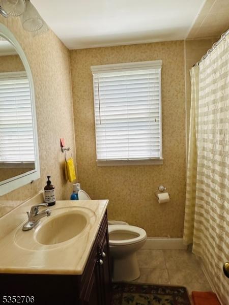 bathroom featuring a shower with curtain, toilet, baseboards, tile patterned flooring, and vanity
