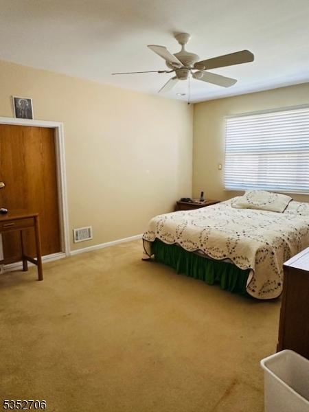 bedroom with light carpet, baseboards, visible vents, and a ceiling fan