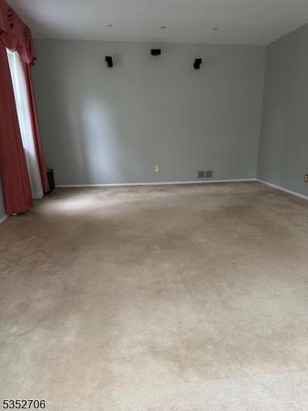 empty room with light colored carpet, baseboards, and visible vents