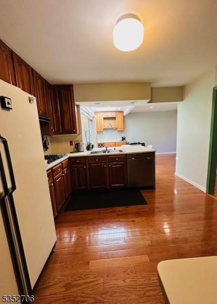 kitchen featuring a sink, dark wood-style flooring, baseboards, freestanding refrigerator, and light countertops