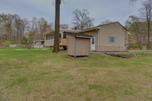 rear view of house with an outdoor structure, a yard, a storage shed, and fence