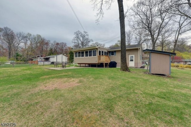 back of house with fence, a lawn, and an outbuilding