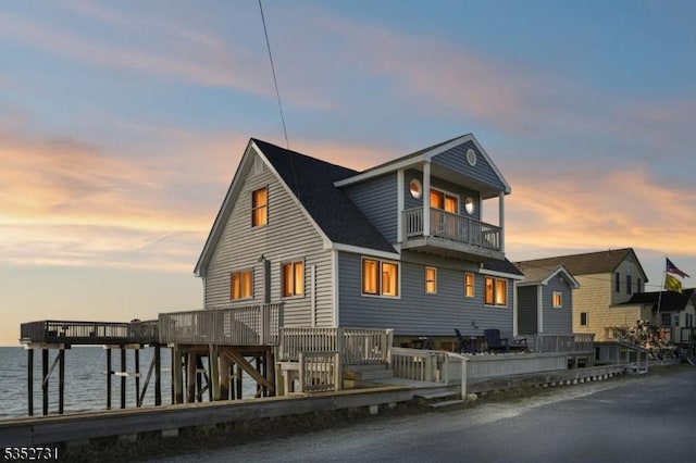 view of front facade featuring a balcony and a deck with water view