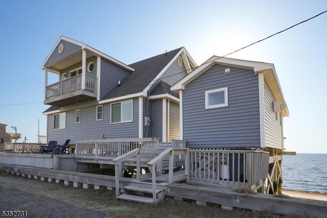 rear view of house with a balcony and a deck with water view