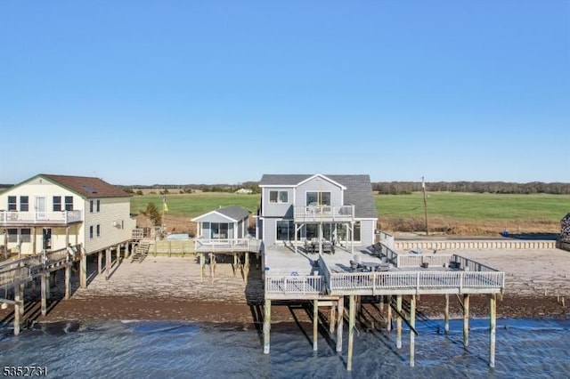 rear view of house featuring a rural view, a balcony, and a deck