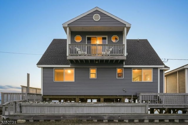 back of property with roof with shingles and a balcony
