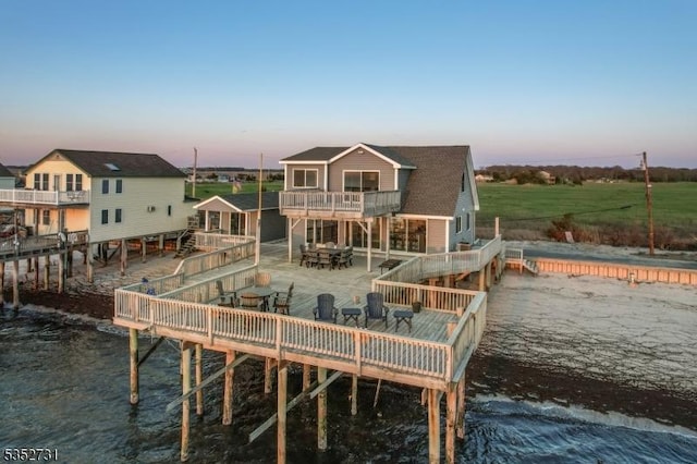 rear view of house featuring a wooden deck, a balcony, and outdoor dining space