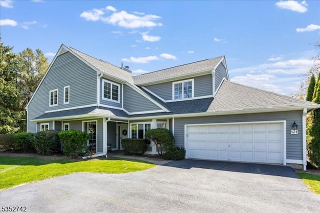 view of front of house featuring a front yard, driveway, a garage, and a shingled roof