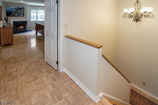 hallway with an upstairs landing, a chandelier, and baseboards