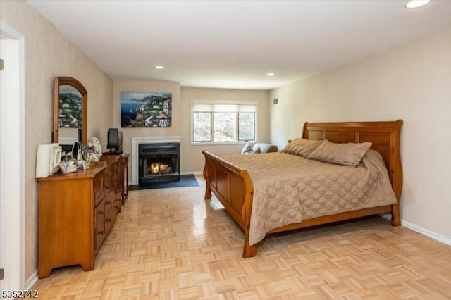 bedroom featuring a fireplace with flush hearth, recessed lighting, and baseboards